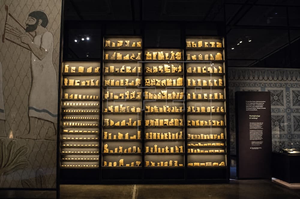 Museumvitrine met veel opgegraven kleitabletten uit Nineve in verlichte schappen