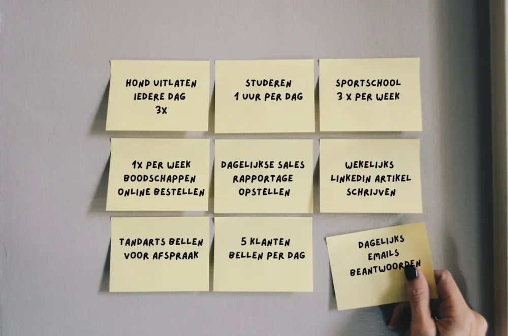 Negen gele plaknotities met taken en gewoontes, zoals studeren één uur per dag, op een muur