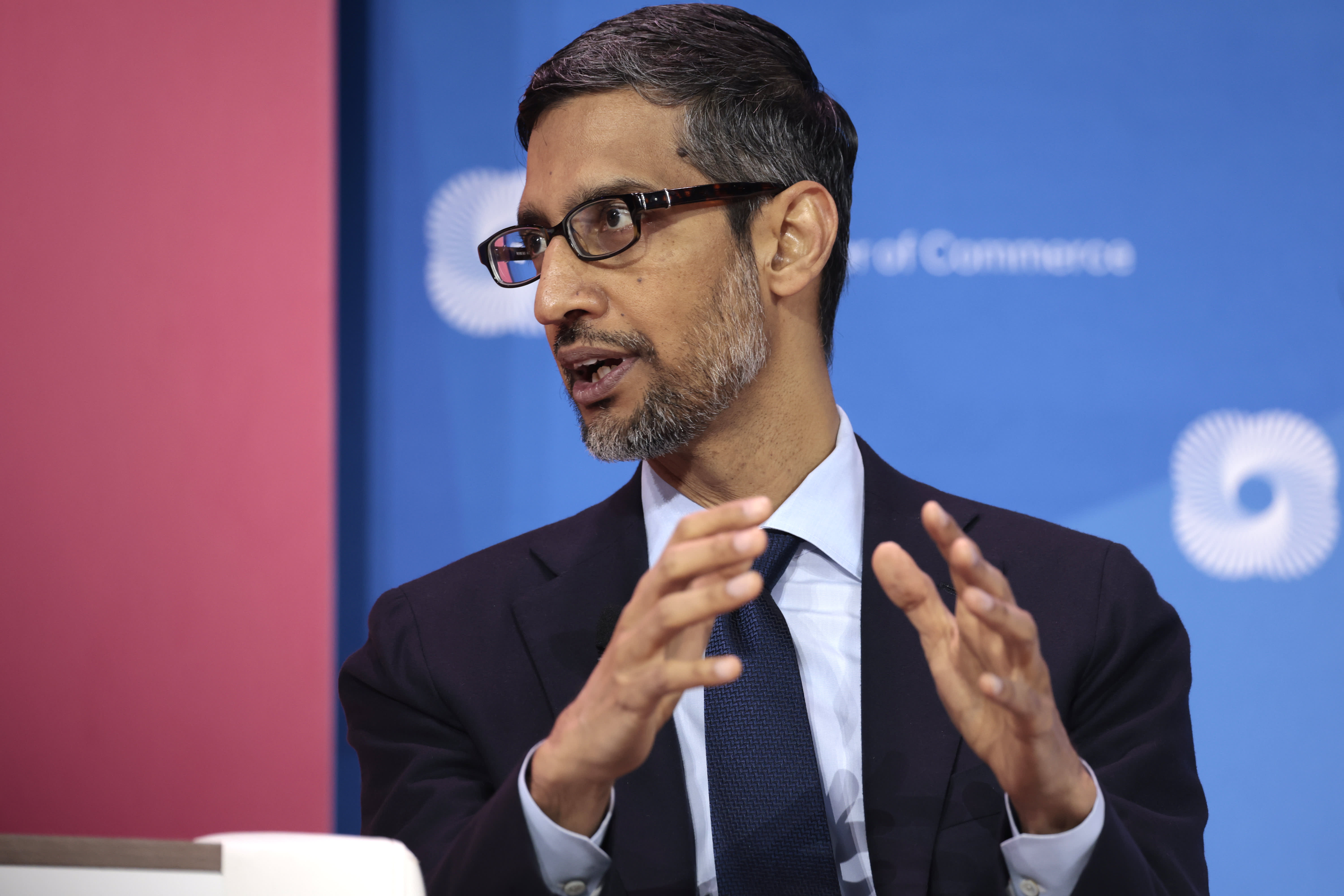 Sundar Pichai praat met gebaren voor een blauwe achtergrond